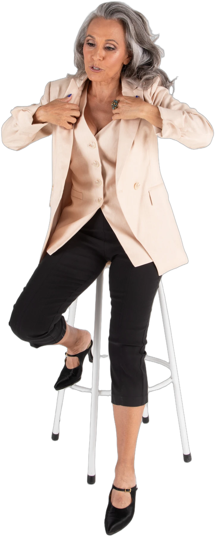 Nicole Jolie seated on a stool in a beige jacket